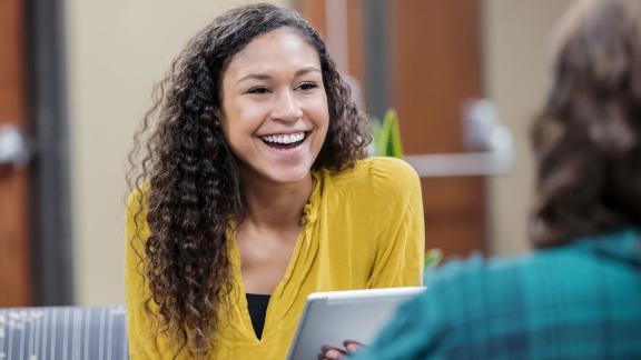 A smiling office worker, holding a tablet and conducting an interview.