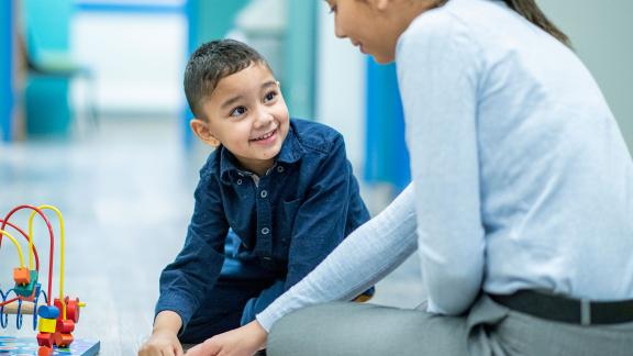 A play therapist with a child, sitting on the floor.