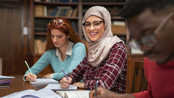 A diverse group of students, studying and smiling.